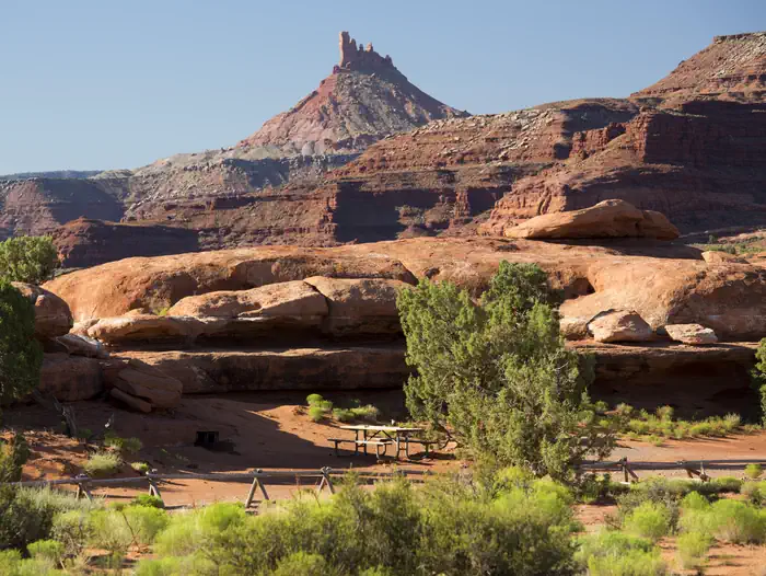 A picnic table adjacent to Hamburger Rock geologic feature with a Six Shooter peak in the background.