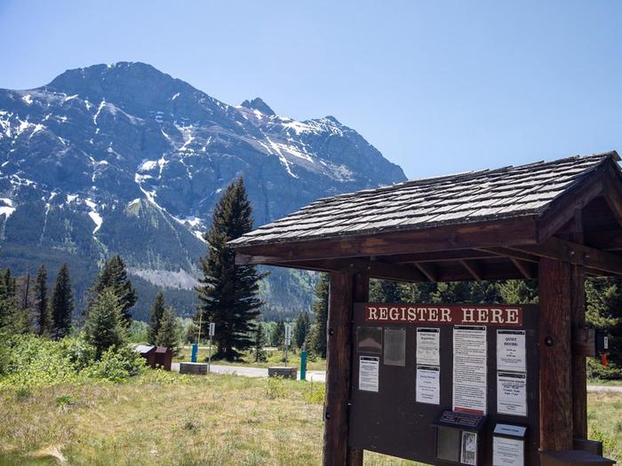 View of campground self-service kiosk with trees and a mountain in the background.