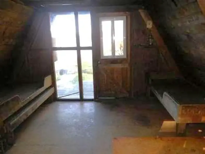 Interior of wood cabin with two wood bunkbeds, window and door