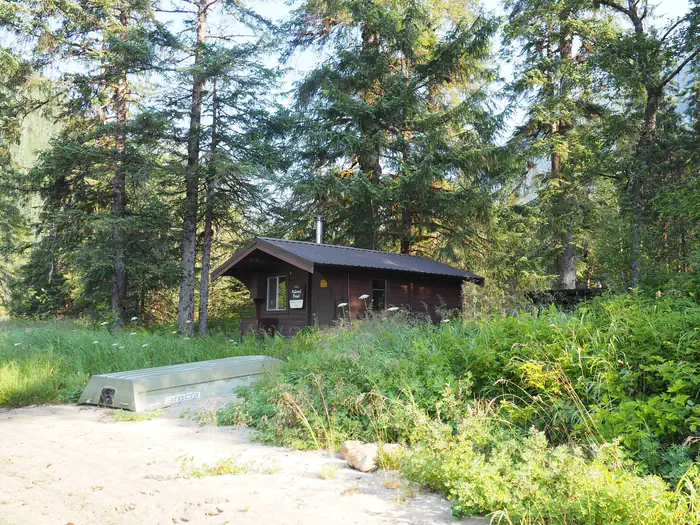 Marten Lake Cabin with overturned small skiff in front with grasses and trees surrounding it