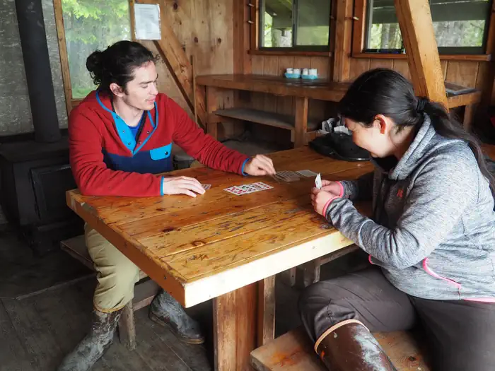 Two people playing cards inside a wood cabin