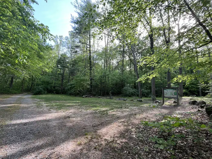 A gravel drive opens to a grassy patch with large rocks bordering