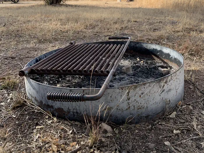 Metal fire pit on the ground at Calabasa campground. Metal ring with an attached metal grill on top.