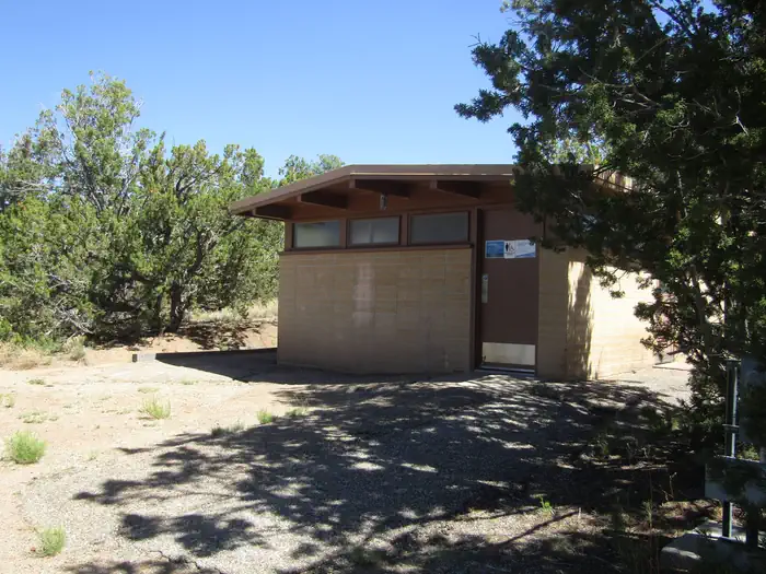 A tan brick building surrounded by juniper.