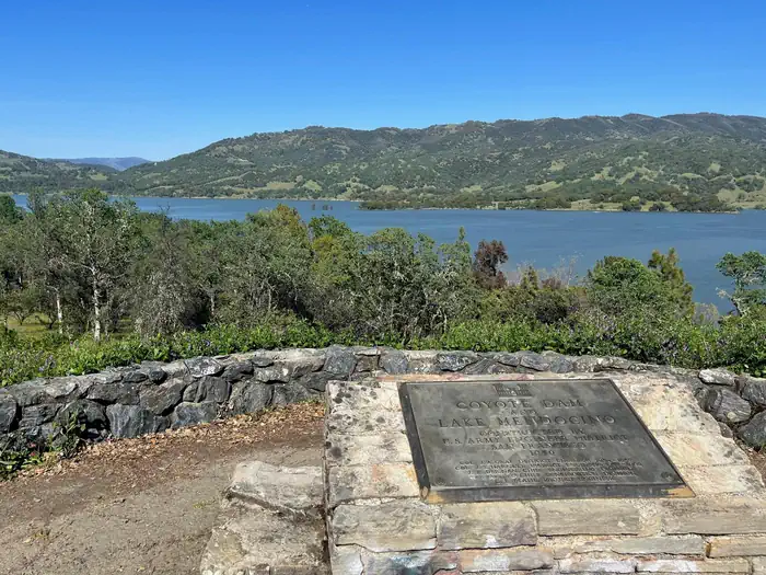 Coyote Dam & Lake Mendocino plaque mounted to stone wall, with view of Lake Mendocino in the background