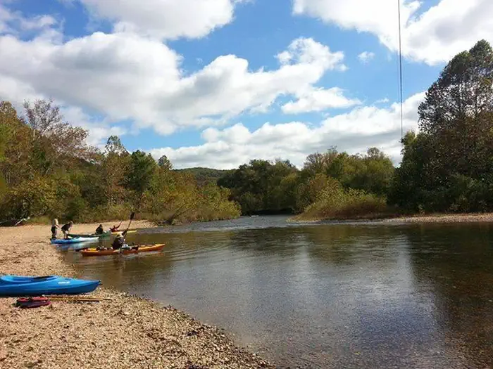 Kayaks on the water and beach at Pulltite under a blue sky with puffy white clouds-preview