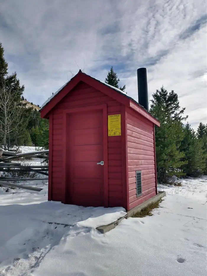Red Outhouse, Surrounded by snow and green trees