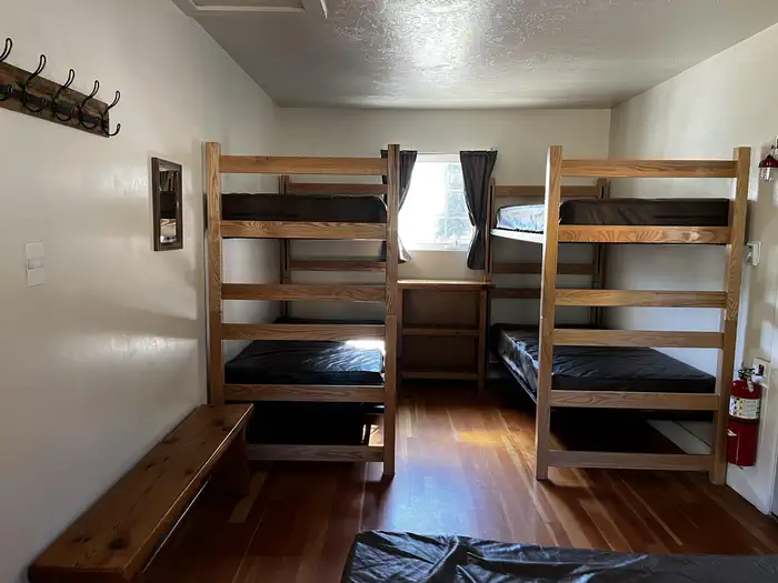 Bedroom showing double bed, two sets of bunkbeds and bench.