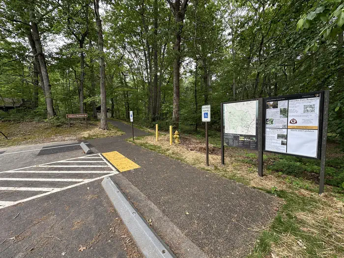 Handicapped parking and a paved walkway beside information signs in a forest