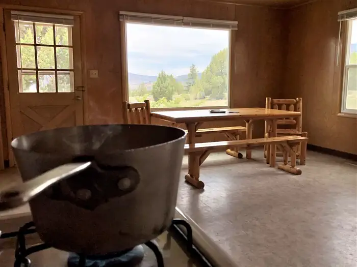 In the kitchen, a boiling pot sits on the gas stove in the foreground of Orange Olsen Dwelling dining area.