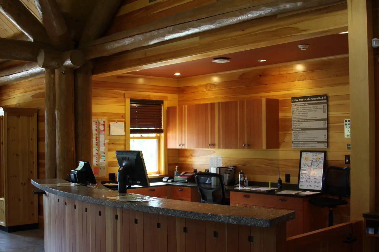 An empty reception desk with heart of pine wood paneling and dim lighting.