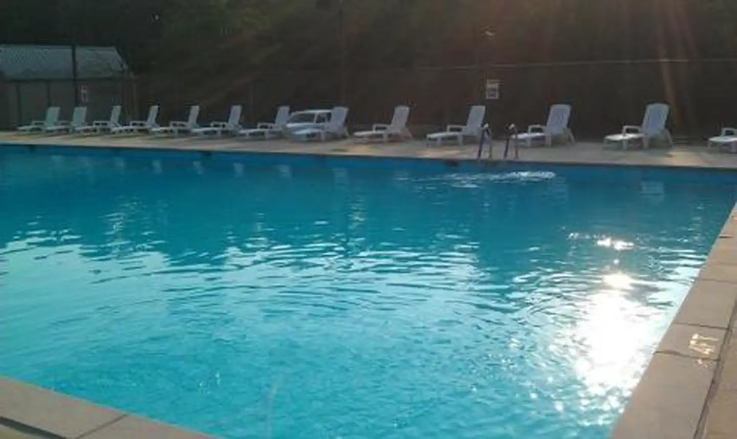 Swimming pool with reclining chairs placed around the edge of the pool