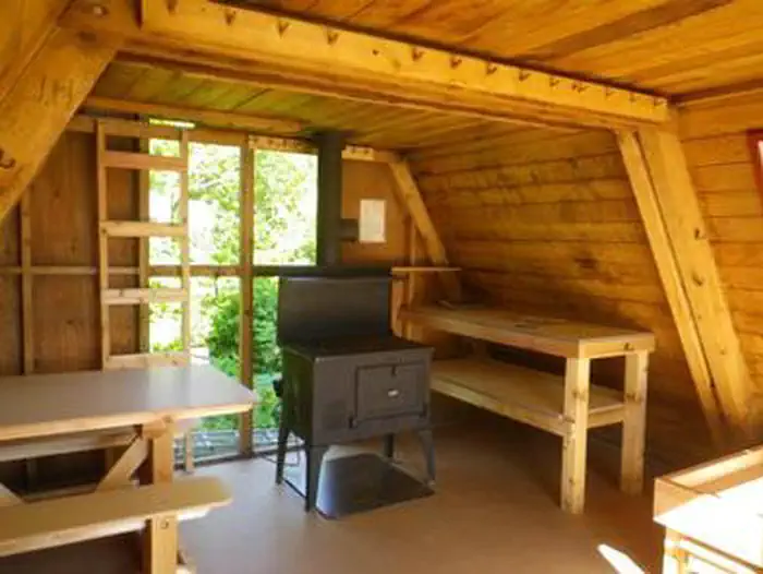 Twin Lakes Cabin scenery (AK) interior showing wood table, shelves and stove