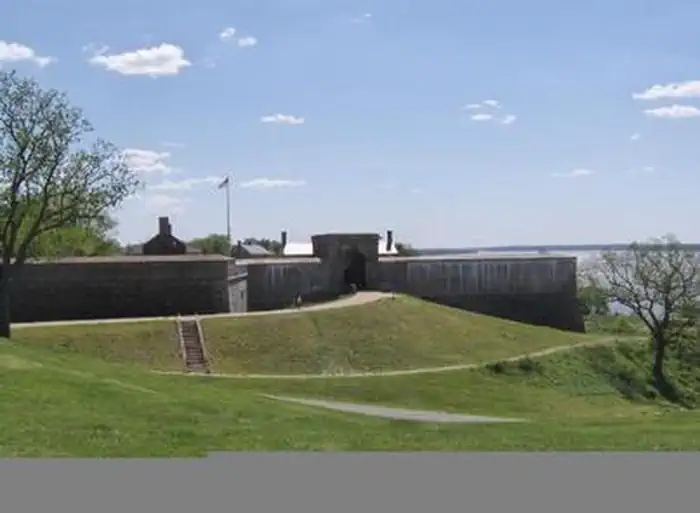 The distance view of the historic fort, showing the sidewalk leading up to the entrance gate.