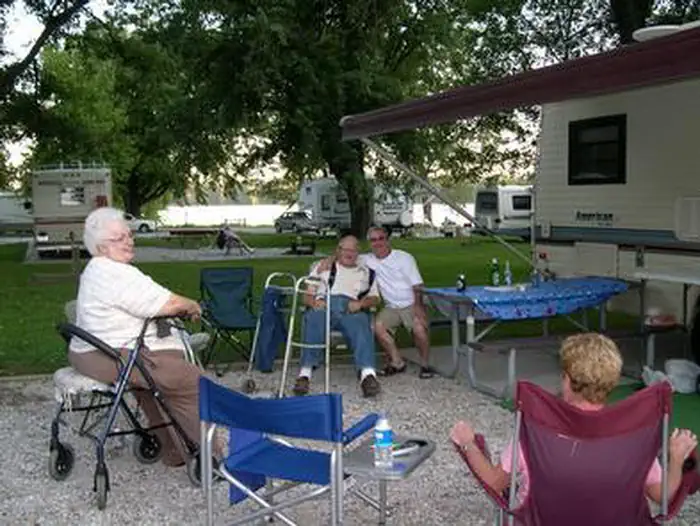 Senior campers using chair assistance and visiting at campsite.